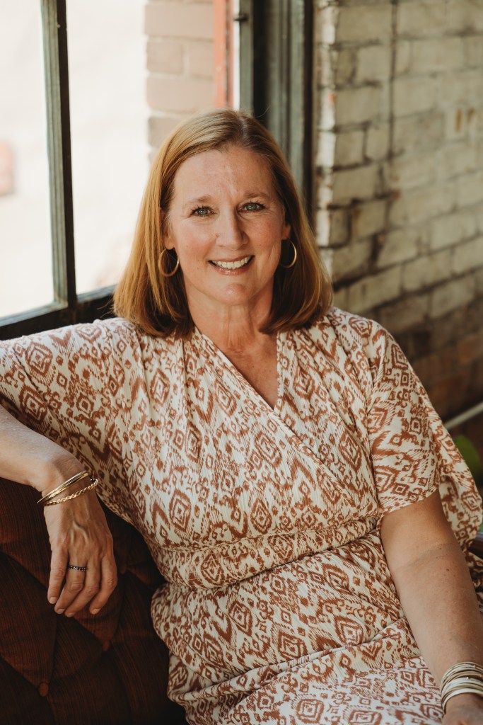 Amy Brown sitting on sofa smiling invitingly