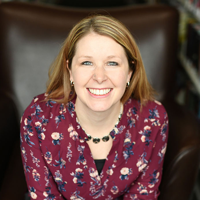 Carrie Holt sitting on chair smiling invitingly